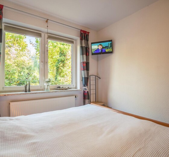 Schlafzimmer mit Bett und TV-Ferienwohnung Louise - Ferienhaus / Ferienwohnung Büsum -  11