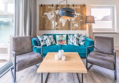 Wohnzimmer mit Sofa und Sessel-deichlodge, lodge.eins - Ferienhaus / Ferienwohnung Büsum - 3