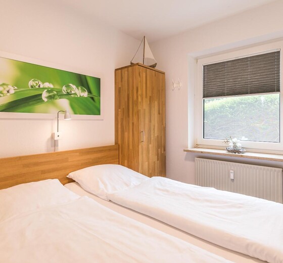 Schlafzimmer mit Bett und Fenster-Ferienwohnung Bamberger`s - Ferienhaus / Ferienwohnung Büsumer Deichhausen -  9